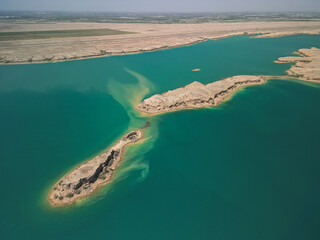 Aerial view of Kuimazar Reservoir in Uzbekistan, where desert sands meet calm blue waters. Distant...