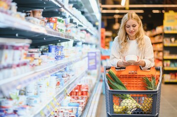 Young cool customer woman wear casual clothes shopping at supermaket store grocery shop buying with trolley cart choose products inside hypermarket