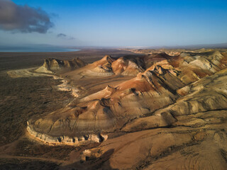 Aerial view rotates over a singular mound of Aktumsik Cape, showing concentric bands. Eroded slopes...