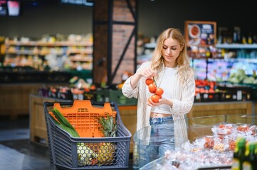 Girl choosing tomatoes in a food store or a supermarket