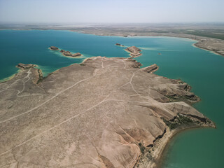 Aerial view of arid headland extending into Kuimazar Reservoir. Distinct water shapes and dry land patterns create a unique natural landscape in Uzbekistan.