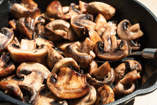 fried mushrooms champignons. on a cast-iron frying pan, natural light, close-up,