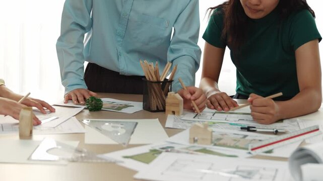 A video of architect use measurement tools and pencil to measure blueprint. Architect design house construction on a table at studio, with architectural plan scattered around. Focus hand. Delineation.
