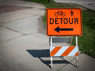 Close-up of a detour sign on a traffic barricade with an arrow, bicycle, and pedestrian icon with copy space. contruction or road work design element. © mailcaroline