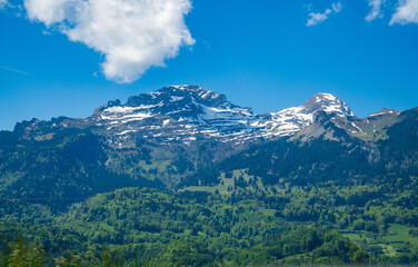 Idyllic landscape in the Alps with fresh green meadows and mountain peaks.