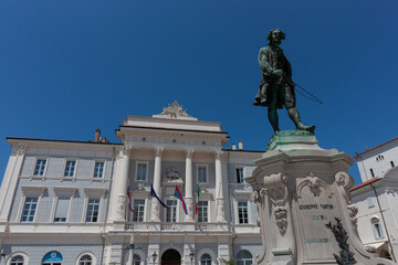 A wide-angle, low-angle shot captures the iconic Tartini Square in Piran, Slovenia, dominated by...