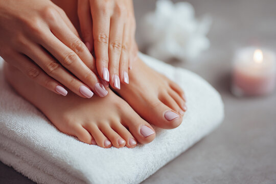Elegant hands applying nail polish on beautifully manicured feet at a spa with calming atmosphere