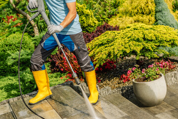 Cleaning Garden Pathways Using a Pressure Washer in Vibrant Landscaped Yard