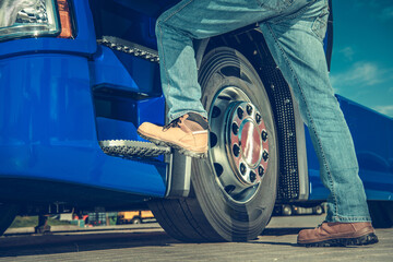 Truck Driver Preparing to Climb Into Large Blue Truck at Transportation Hub