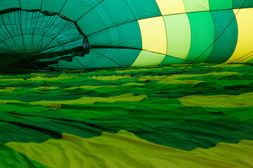 Obraz premium Inside view of a colorful hot air balloon during inflation, with a person in the distance, capturing the anticipation and thrill of adventure travel and ballooning experiences.
