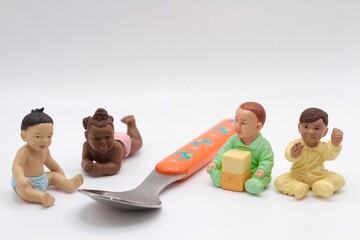 miniature baby figurines next to a weaning spoon