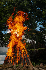 Fire dancer. The fire dances. Tall bonfire burning intensely with orange flames reaching high,...