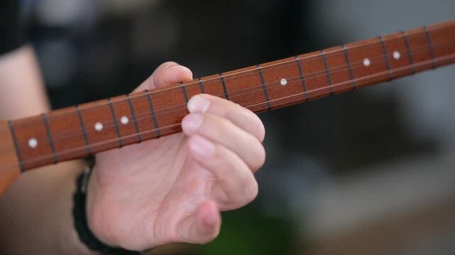 Solo saz performance by a seated man &ndash; close-up of fingers and strings
