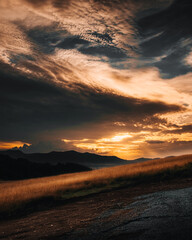 Spectacular sunset in the mountains, with rays breaking through dramatic clouds, illuminating golden grasses in the hills