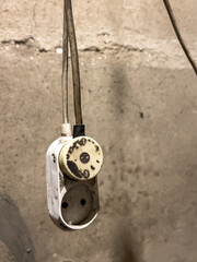 An old, dirty electrical outlet with a wire hanging from a neglected wall, symbolizing an old installation and risk