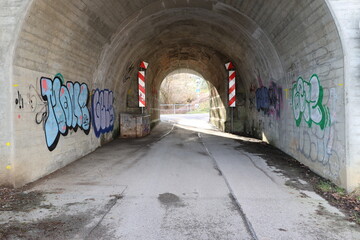 A tunnel with graffiti on the walls and a sign that says 