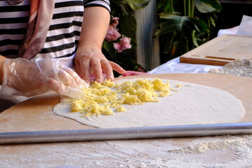 A woman who makes gözleme dough with a rolling pin. Traditional Turkish cuisine. Pastries. A close-up of a woman's hand rolling dough. Bakery products. Rolling out thin pastry dough.