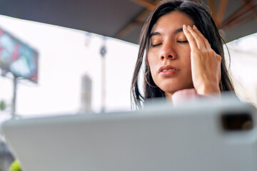 Stressed freelancer suffering headache working remotely from coffee shop