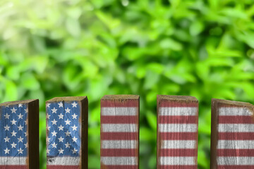 Wooden fence with painted American flag on green lawn, Independence Day patriotic background with copy space. rural home scene for patriotic celebrations like Labor Day, Thanksgiving, Columbus Day