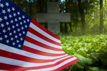 American flag on veteran grave with cross headstone in cemetery background, symbolizing military...