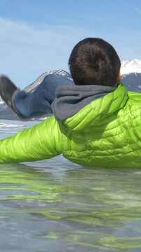 SLOW MOTION, CLOSE UP, LOW ANGLE: Unrecognizable man walking along frozen Lake Abraham slips and falls on the hard ice. Funny shot of a man crashing on his behind as he walks across a frozen lake.