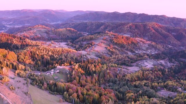 Ukraine, drone, flight in the Carpathians early in the autumn morning at sunrise near the city of Kosiv. Bright forests and dwellings of the Hutsul highlanders on the glades