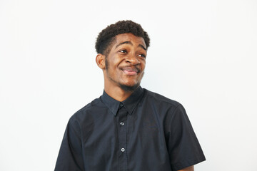 A cheerful African American man with a playful smile, wearing a black shirt, stands against a white...