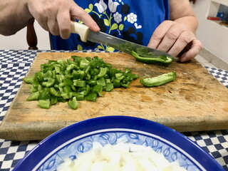 Elderly Woman Slicing Green Peppers on Wooden Board