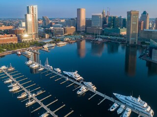 Aerial view of luxury yachts docked at Inner Harbor Marina in Baltimore, Maryland, USA. The photo showcases the city's skyline and waterfront.
