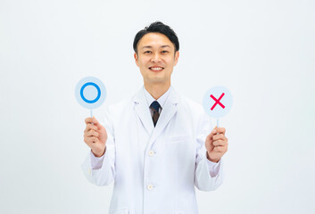 マル印とバツ印を見せる白衣のミドルエイジ男性医師・科学者・研究者