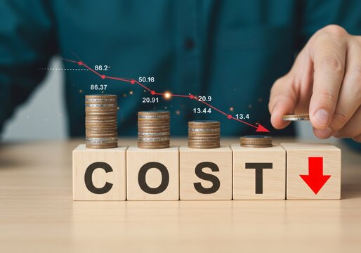 Businessman use magnifier glass and down arrow with decreasing of coins stacking for cost reduction in factory and business cost saving to get more profit concept.