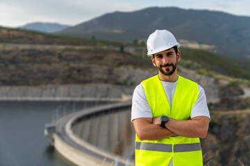 Engineer supervising water resources and renewable energy at a dam, smiling with the dam visible in the background