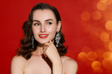 Smiling woman with perfect makeup on red background, bokeh effect