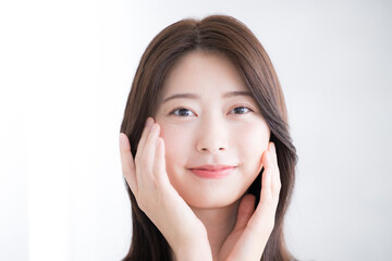 美しい若い女性の素肌感が美しい健康的な笑顔　カメラ目線で両手を添える　美容やビューティーイメージ