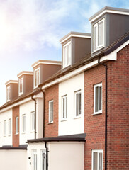 Houses – row of modern terraced homes in neighbourhood street. Terraced UK town houses typical architecture.of urban street areas on sunny summer day. Real estate market opportunity.