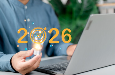 Businessman holding light bulb with target 2026 for preparation happy new year concept. New...