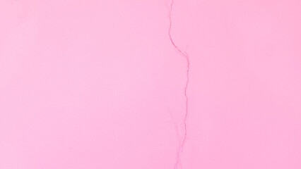 Pink concrete wall has cracks due to poor quality construction. Cracked wall surface