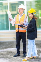 Two Asian male and female engineers inspecting work Two female architects are working and inspecting the building with a male engineer.