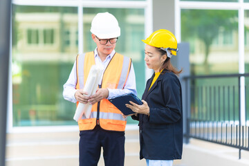 Two Asian male and female engineers inspecting work Two female architects are working and...