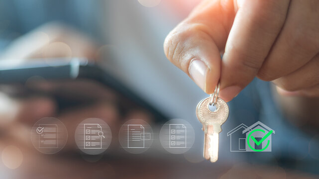 A person holding a house key with digital check mark icons.