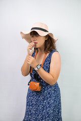 Beautiful young asian woman wearing blue summer dress and beach straw hat is suffering sore throat...