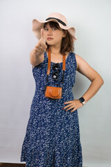 Happy beautiful young asian woman wearing blue summer dress and beach straw hat is showing thumbs...