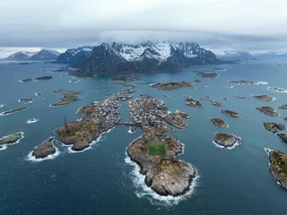Gordijnen Poolcirkel Aerial View of Henningsvær Football Field on Rocky Island Surrounded by Norwegian Sea – Iconic Lofoten Landmark with Colorful Village and Snow-Capped Mountains in Background  © ultramansk