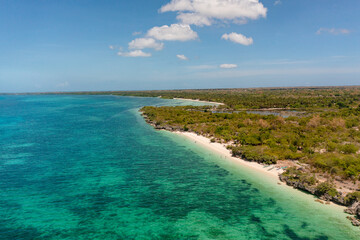 Coral reefs on turquoise water. Tropical sandy beach with white sands. Blue sky and clouds. Bantayan Island. Cebu. Philippines.
