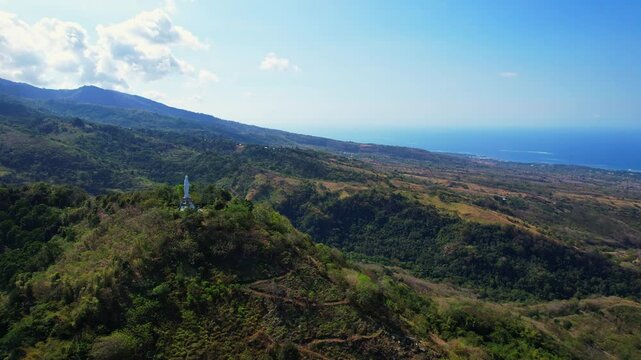 Aerial drone shot of Nilo viewpoint, with a white Mary statue, on top of all the city of Maumere, Flores island, Indonesia