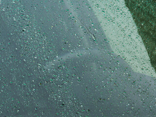 Raindrops on car windshield in urban setting during rain