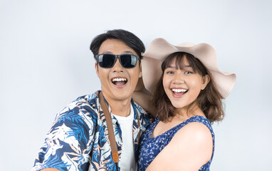 Happy young Indonesian tourist couple in summer clothes is taking selfie photo during holiday...