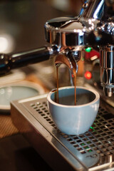 Close up of fresh espresso flows from coffee machine into a cup