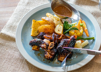 Close up view of person cuts grilled spare ribs with knife and fork