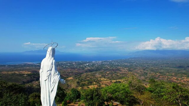 Aerial drone shot of Nilo viewpoint, with a white Mary statue, on top of all the city of Maumere, Flores island, Indonesia
